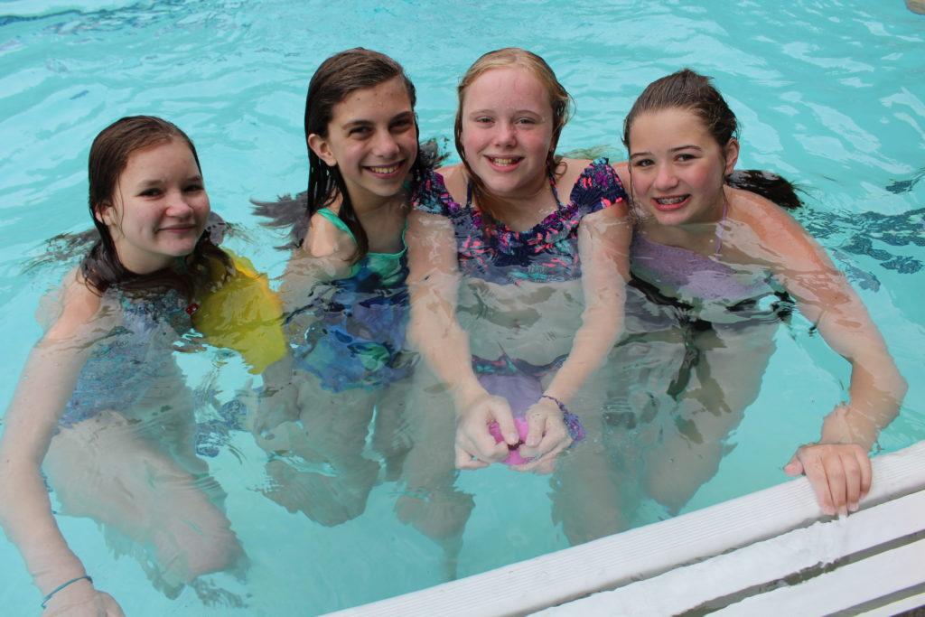 Campers smile for the camper while swimming in the pool