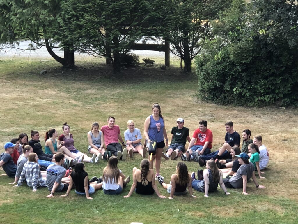 A group of young adult staff members during summer, playing a game in a circle