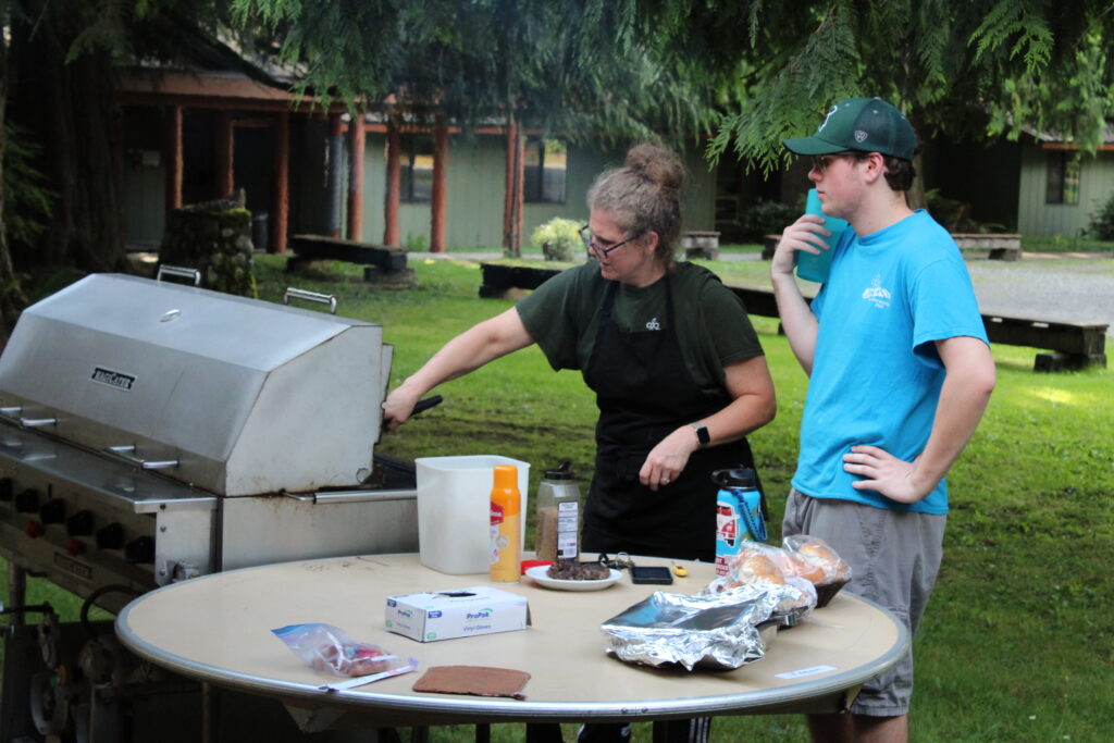 A shot of a staff member frying burgers on a grill outside during summer
